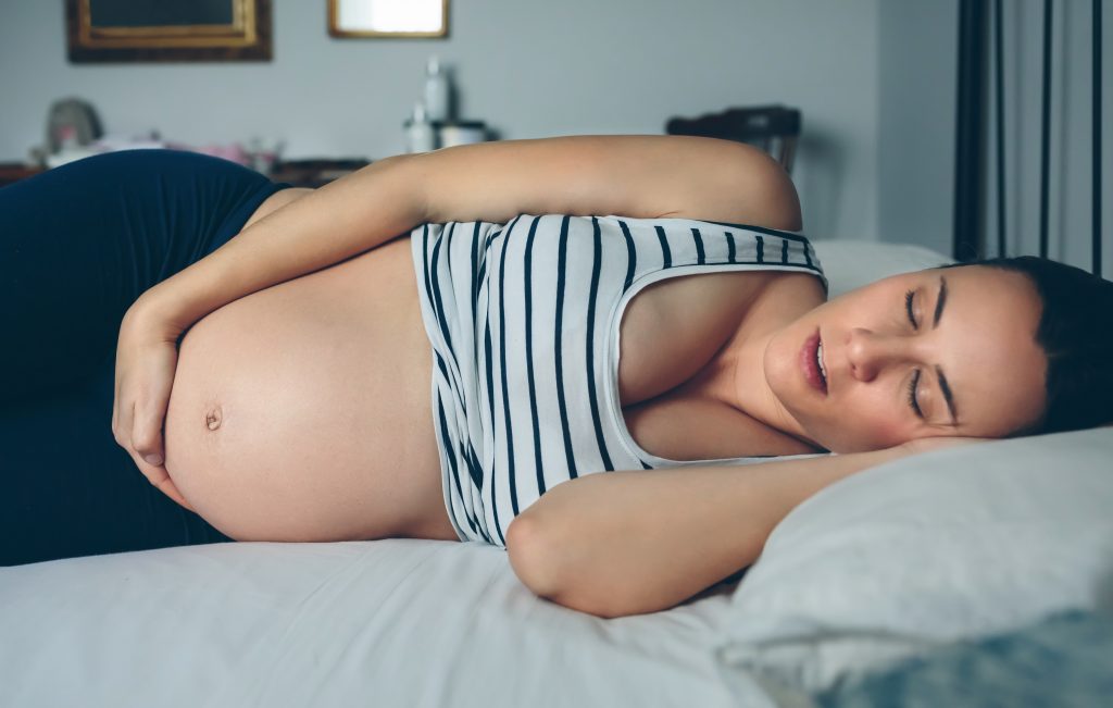 Pregnant woman sleeping on her side in bed