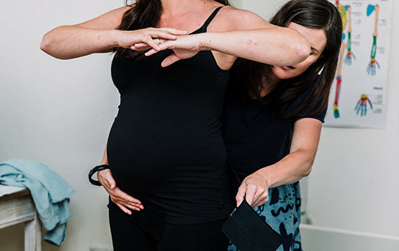 Pregnancy osteopath fitting a pelvic belt on a pregnant woman