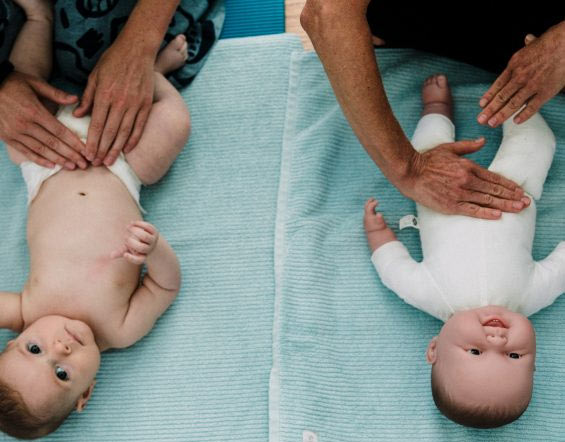 Massaging a baby with teacher demonstrating on a baby doll
